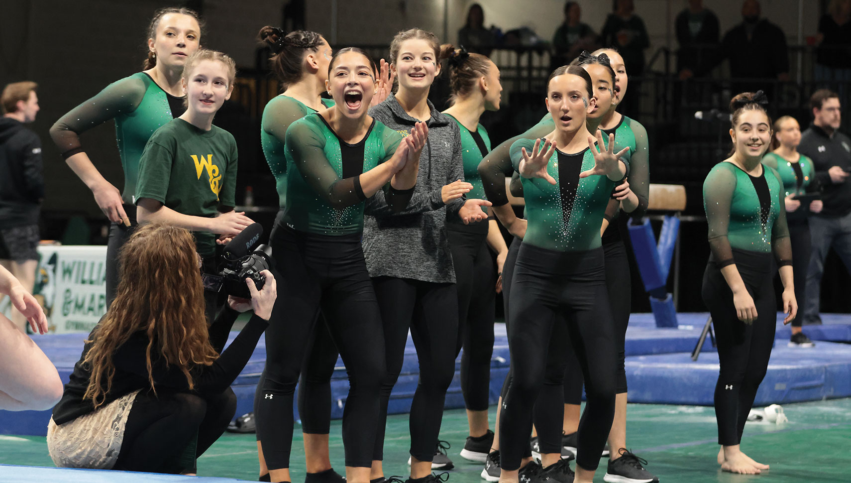 women's gymnastics team looking on at a meet