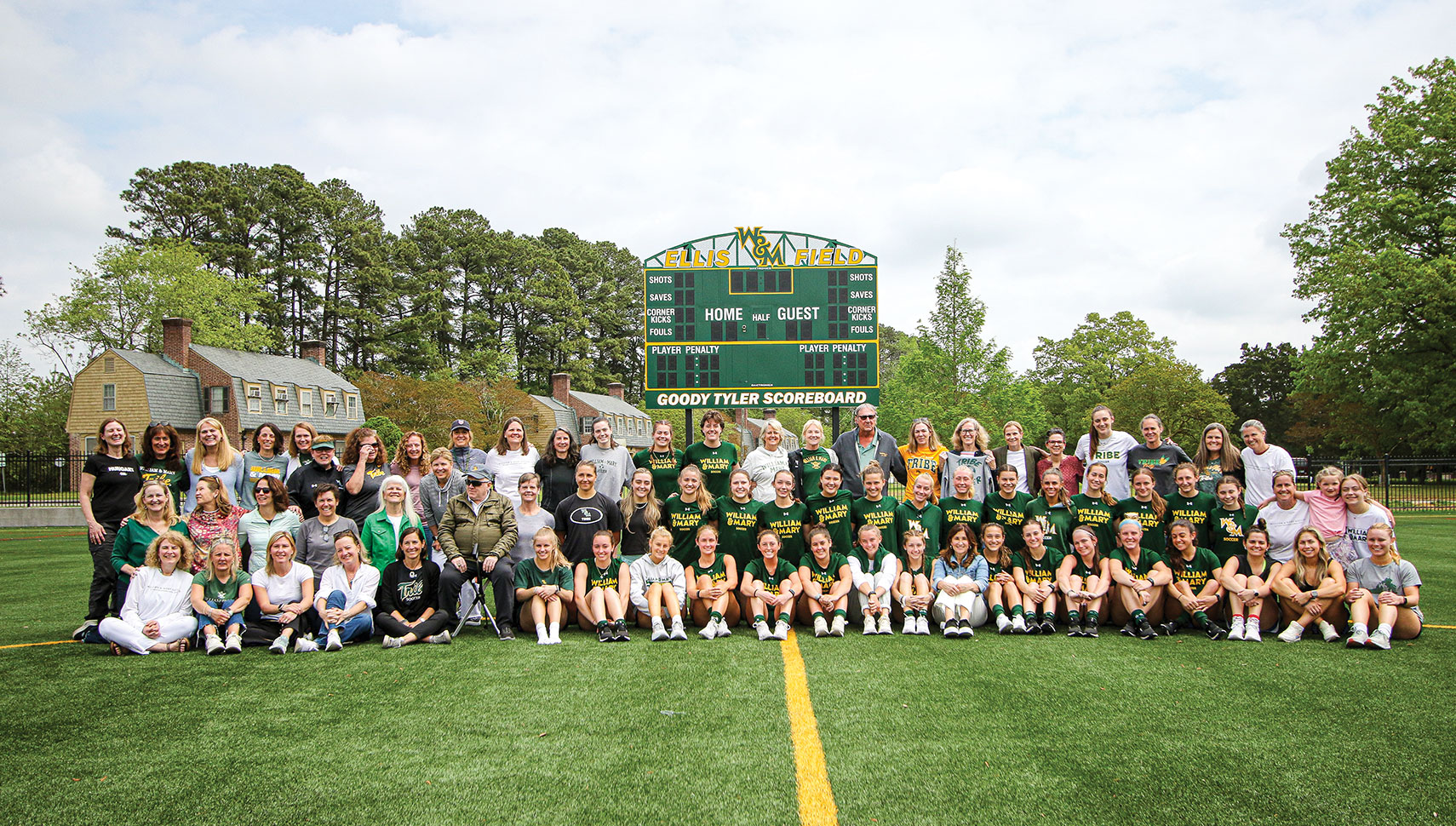 large group photo of athletes and supporters in front of scoreboard