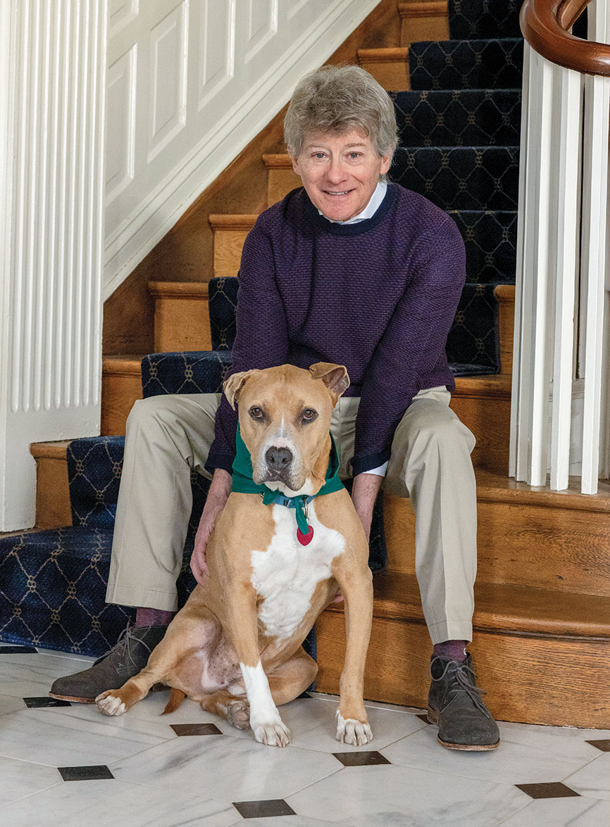 Dr. R. Todd Stravitz '82 sitting at the base of stairs with his dog