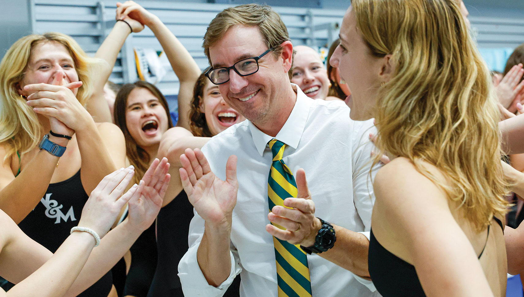 Nate Kellog, coach of men and women's swim, celebrates with the team