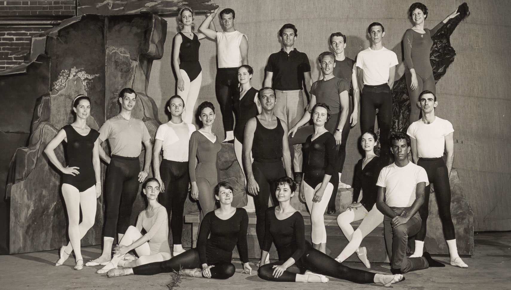 A black-and-white group portrait of young dancers in practice clothes