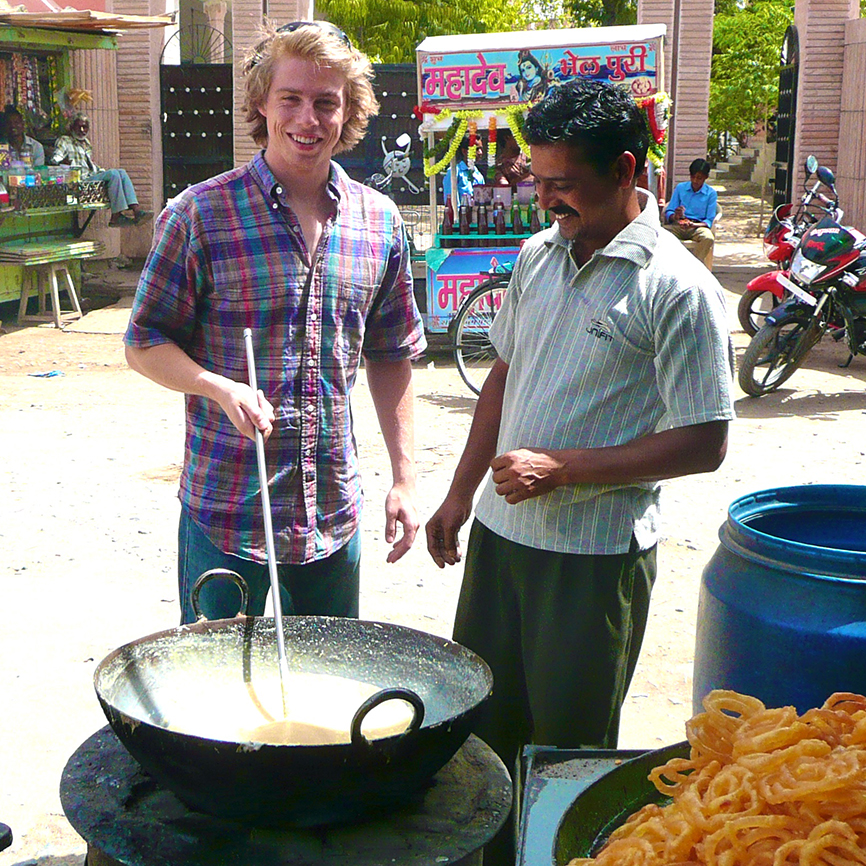 two men cooking outside in wok-style pan