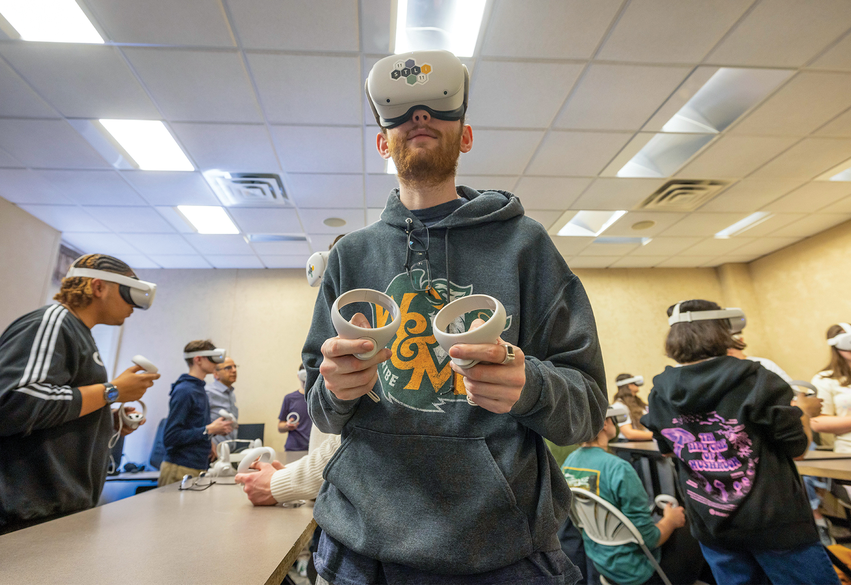students wearing VR headsets and holding gaming controls in a classroom