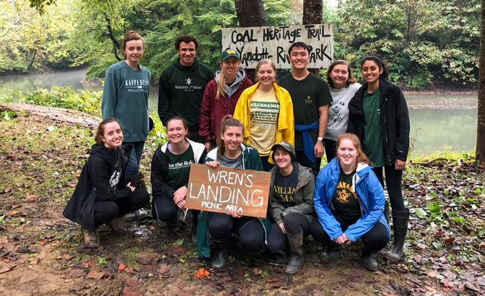 A group of students in a natural area with a handmade sign for Wren's Landing Picnic Area