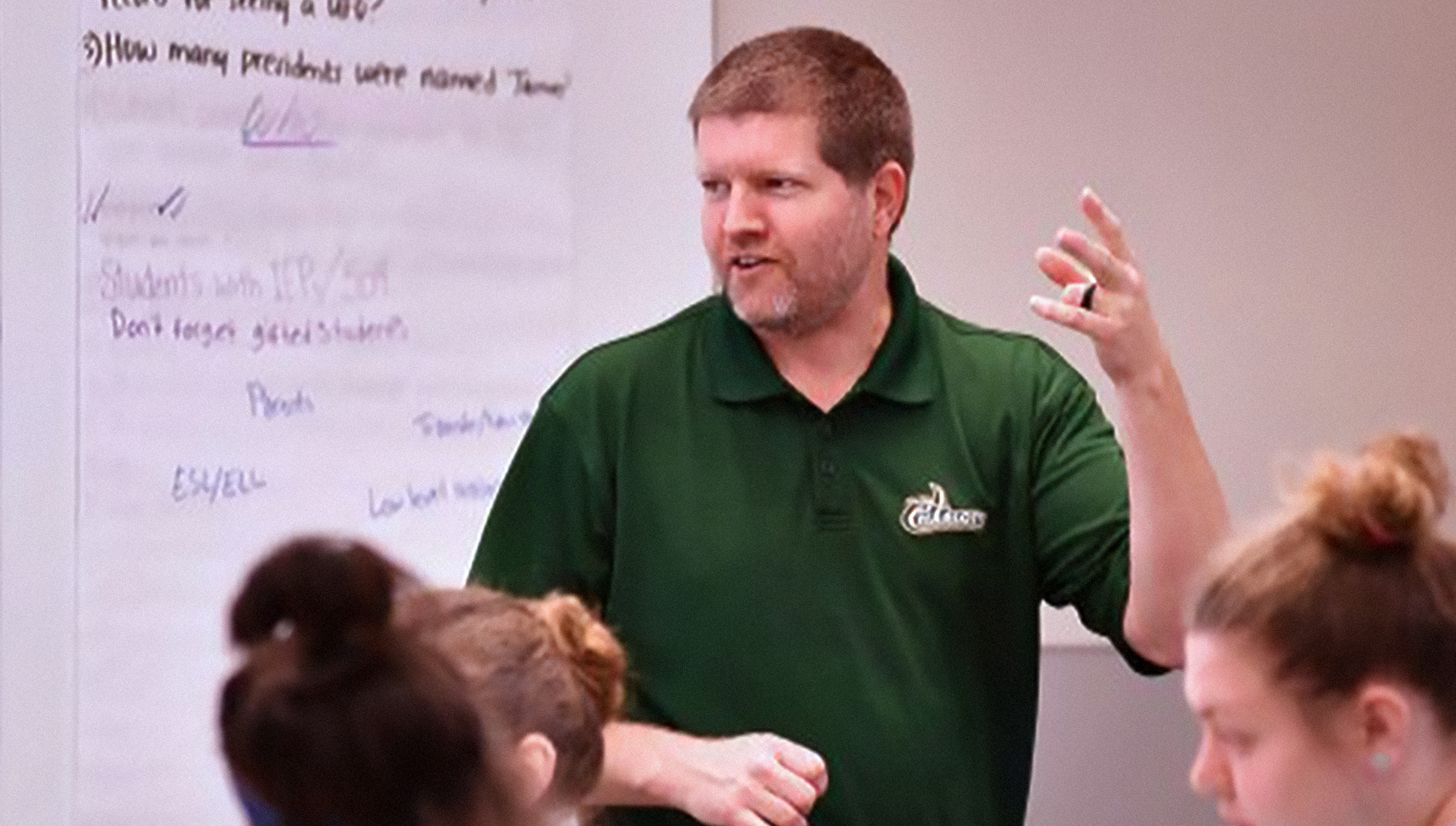 teacher speaking in front of a white board
