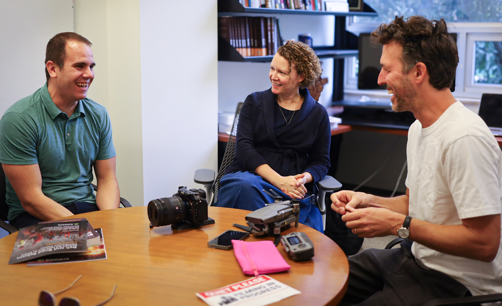 Two men and a woman sitting around a table talking
