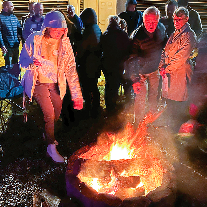 people around open fire tossing in holly sprigs