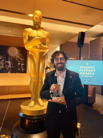 Arjun Fischer poses with the award he won for his documentary.