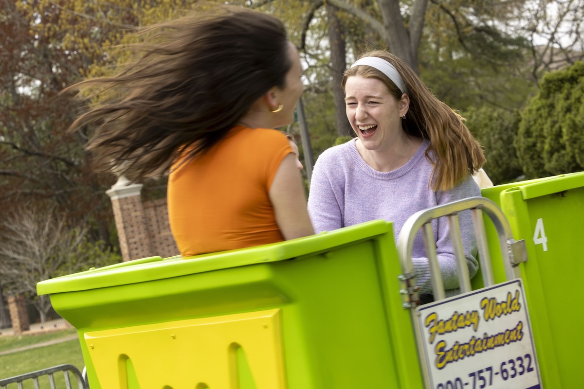 Two students enjoy a carnival ride in the Sunken Garden during One Tribe One Day, celebrating the annual day of giving with spirit.