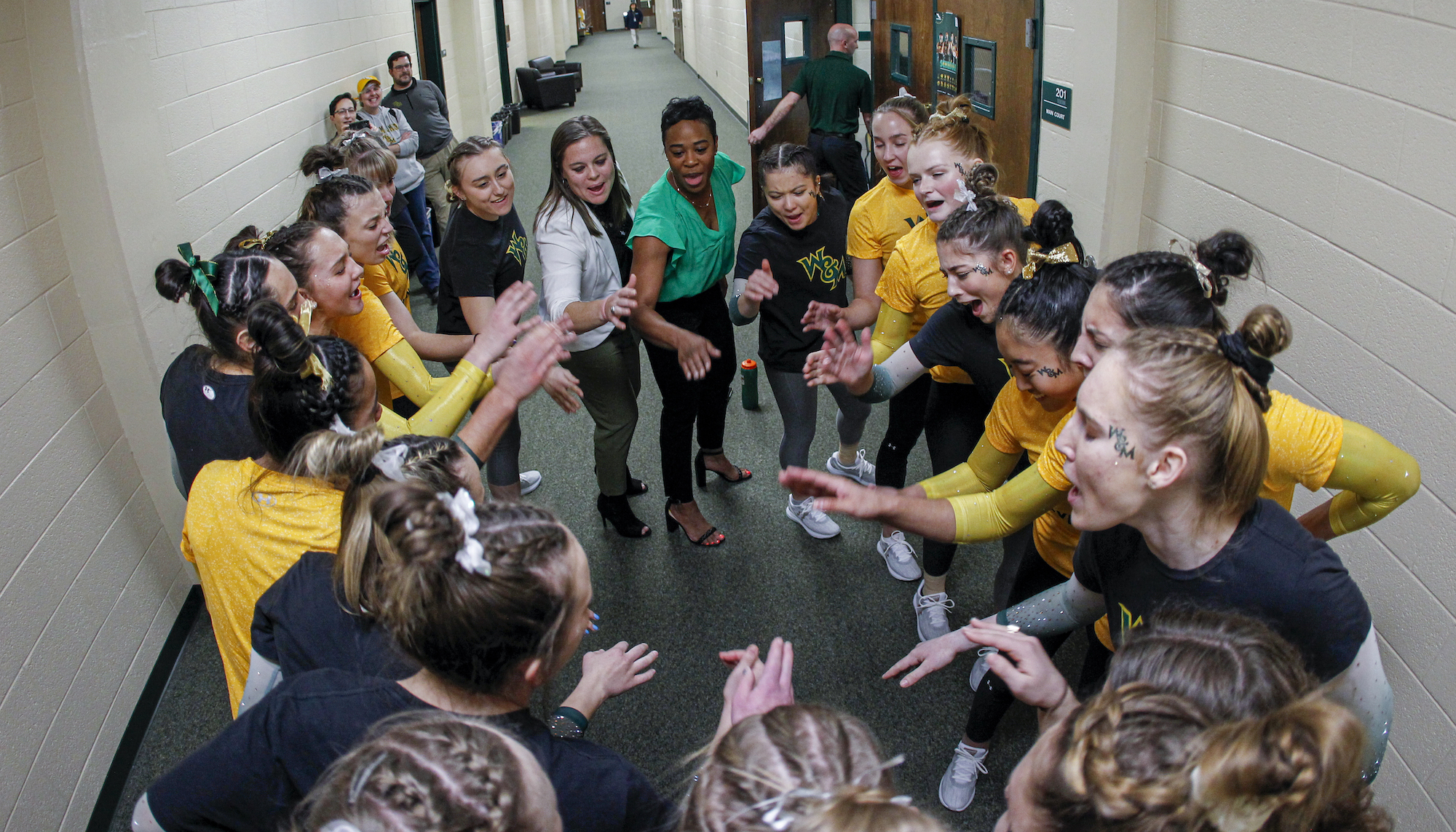 The 2022 women's gymnastics team in a huddle before a meet