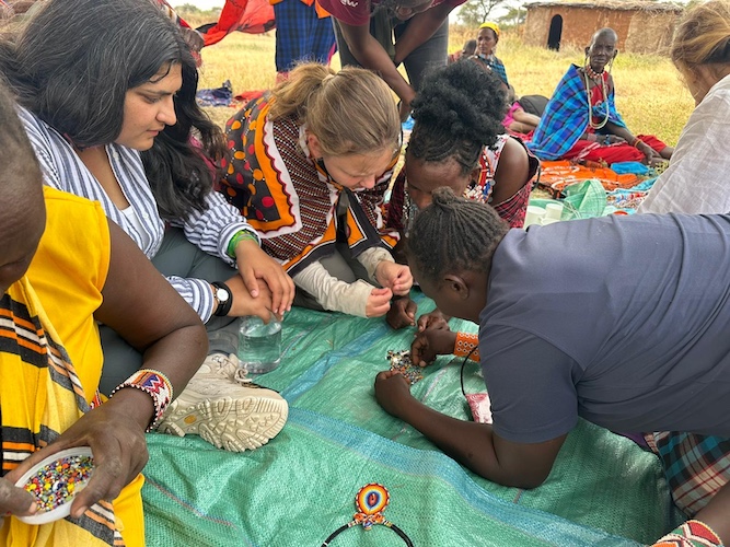 Sydney Hintz and Asha Nair are shown beading with a Maasai women’s collective